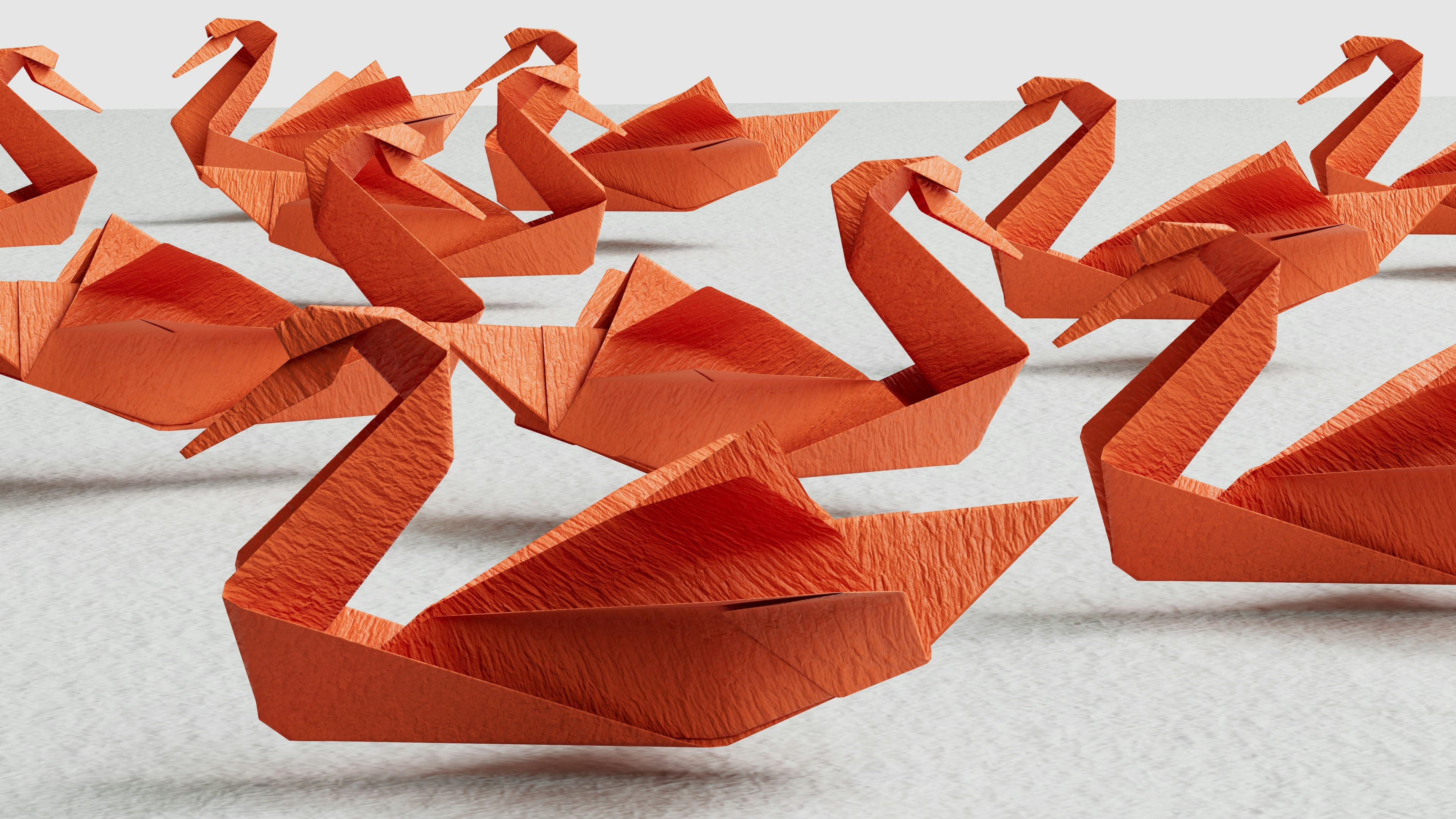 a row of orange origami swans are floating on a white surface .