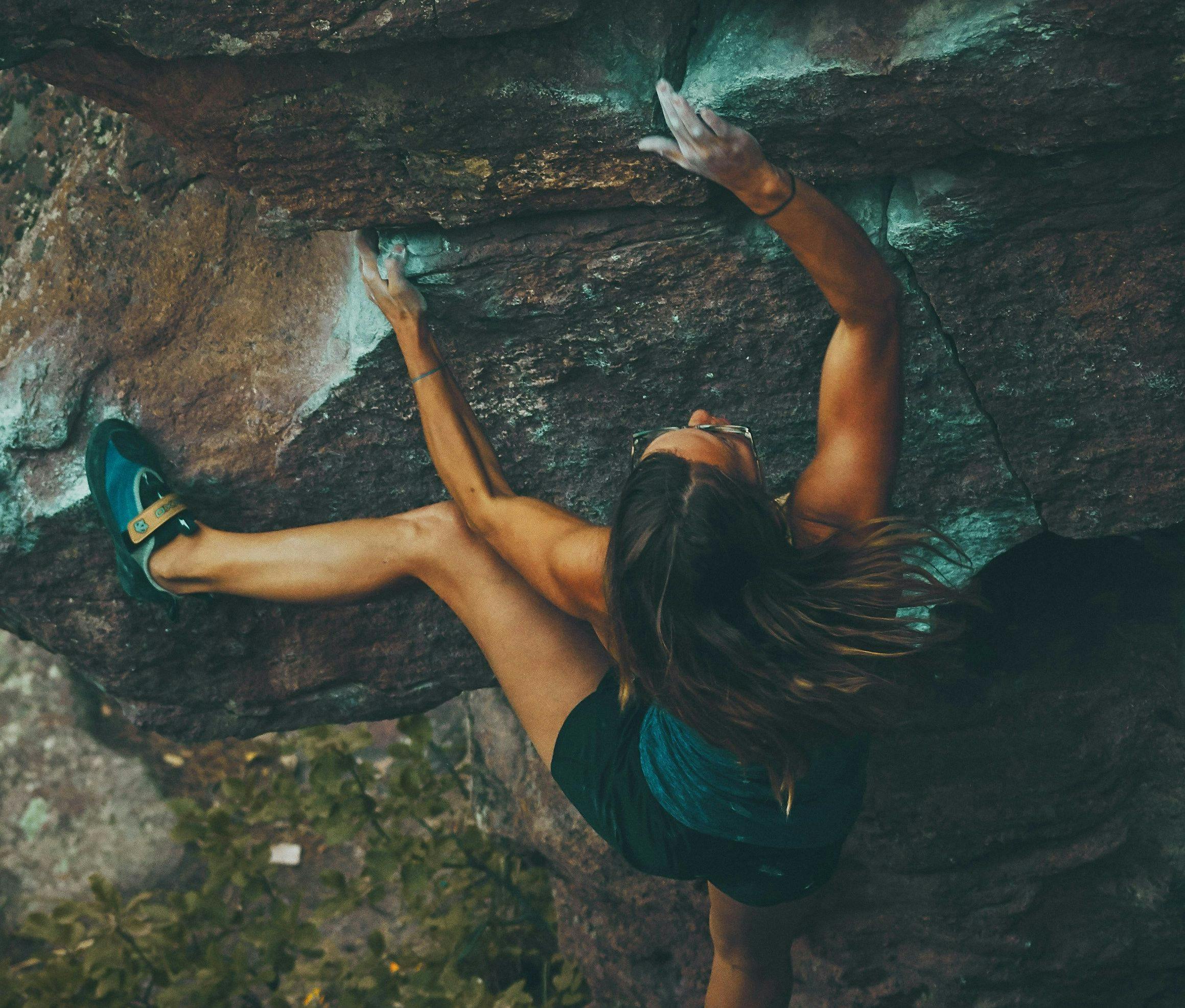 en kvinne klatrer opp en stor stein
